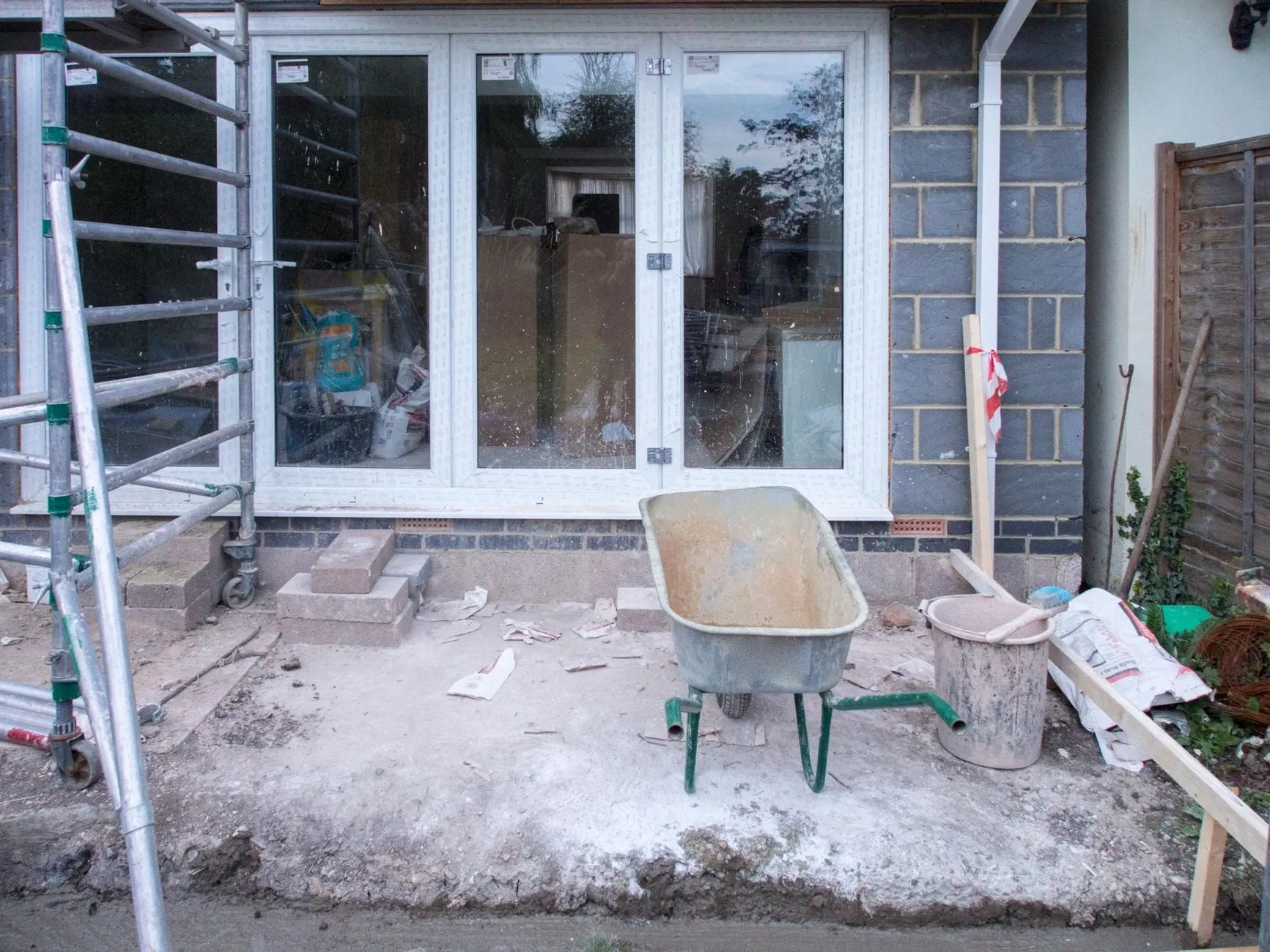 New glazed doors fitted in a rear extension, a scaffold tower and wheelbarrow outside