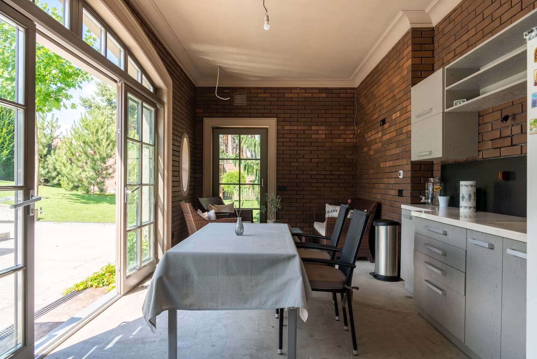 A finished kitchen-diner extension with tall glazed doors open to the garden and an exposed brick wall