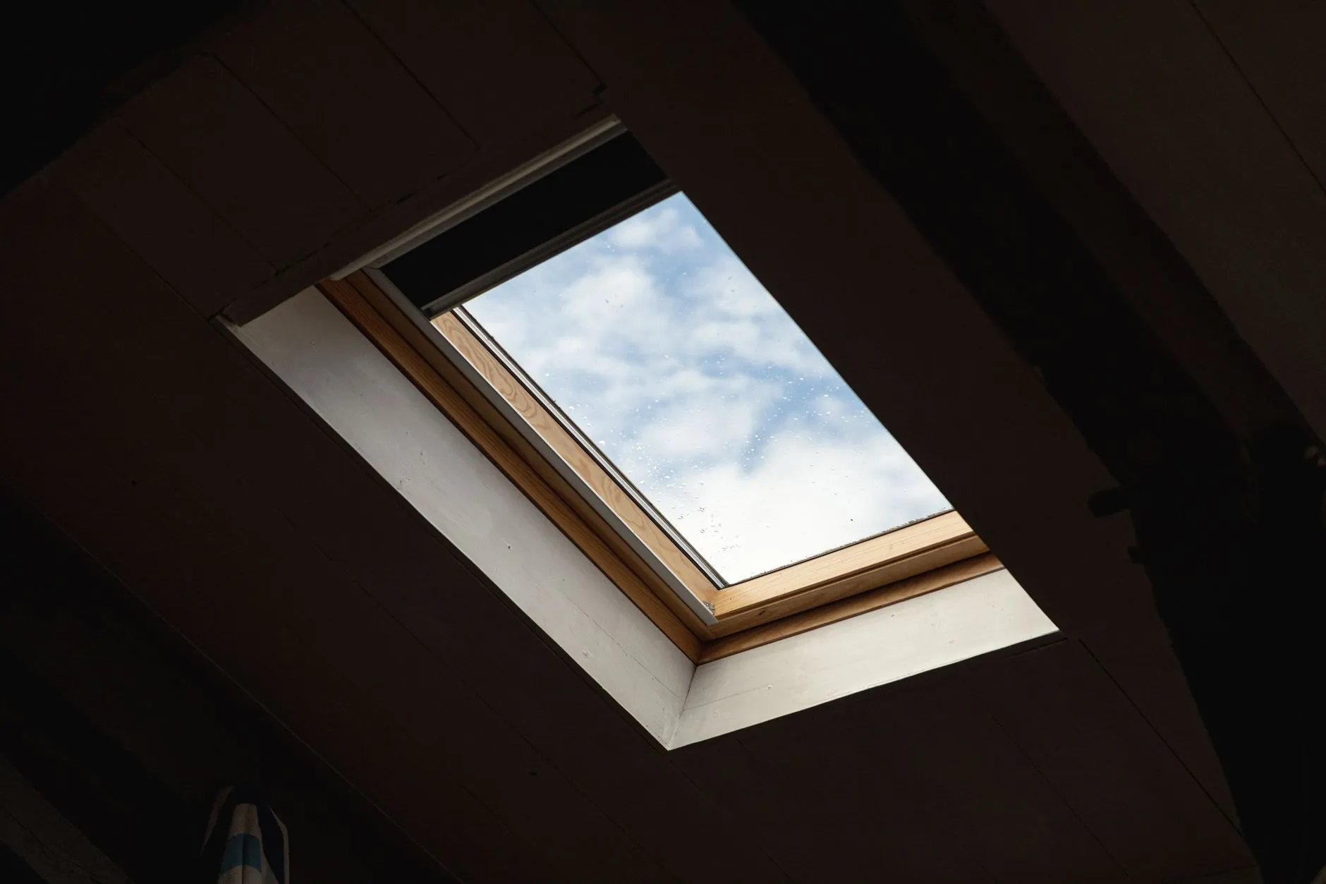 A new timber-framed rooflight set into the sloping loft ceiling, sky beyond