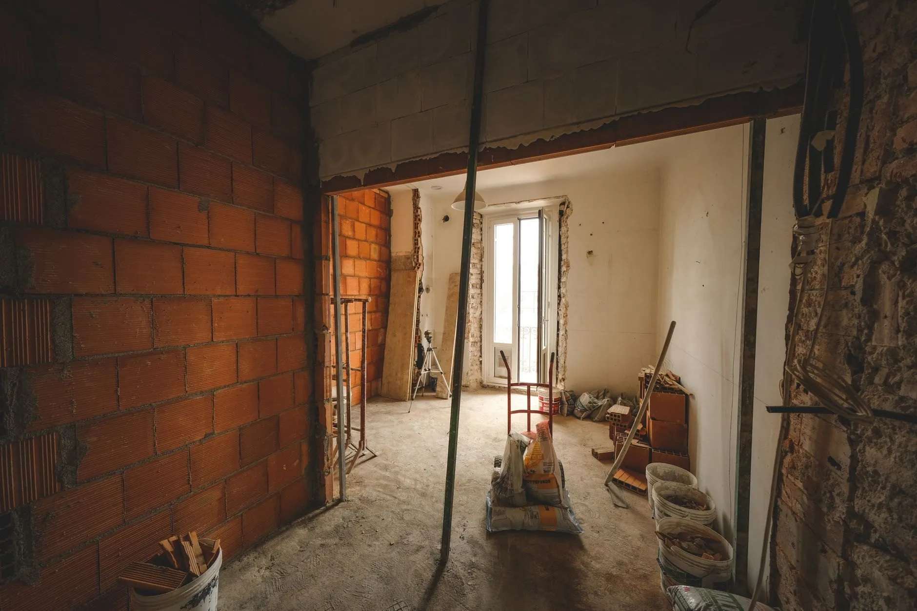 A wide new opening formed through a brick wall, looking through to a bright room beyond