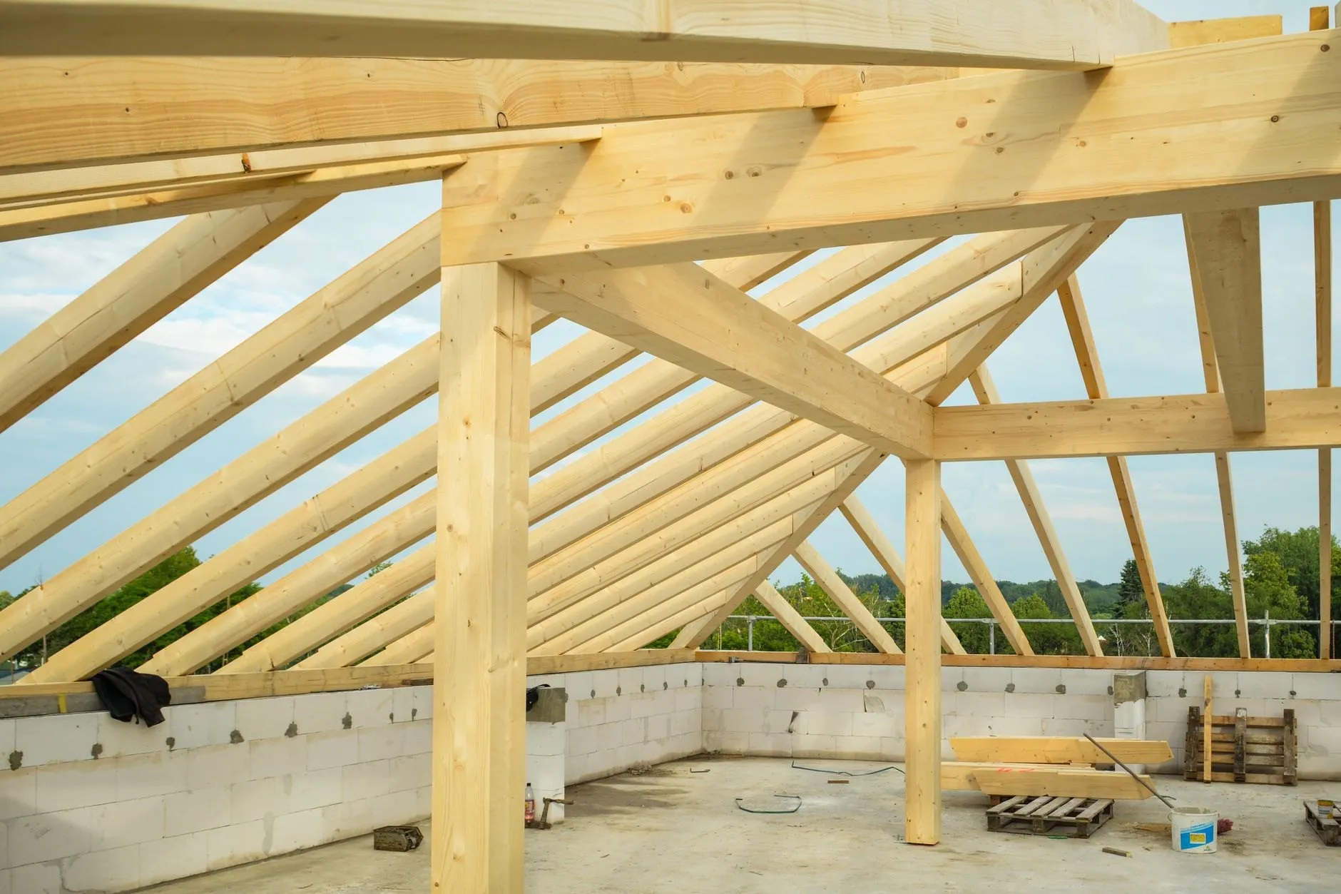 New roof timbers and a ridge beam framed against the sky above fresh blockwork